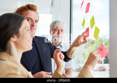 Businessman discussing over blank sticky notes with colleagues Stock Photo