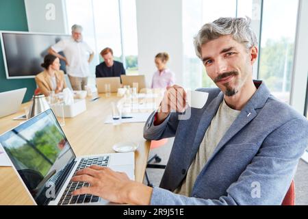 Portrait of businessman drinking coffee while using laptop Stock Photo