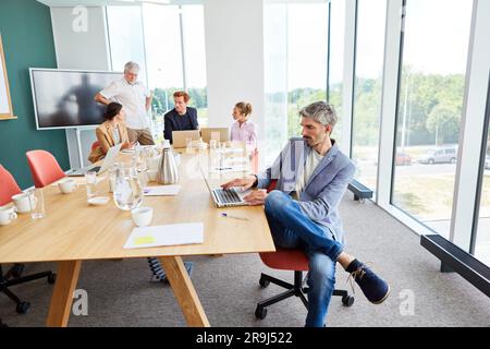 Male professional using laptop sitting at table in conference room Stock Photo