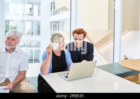Businesswoman holding cup while discussing over laptop with businessman Stock Photo