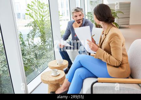 Businesswoman discussing over documents with businessman in lounge Stock Photo