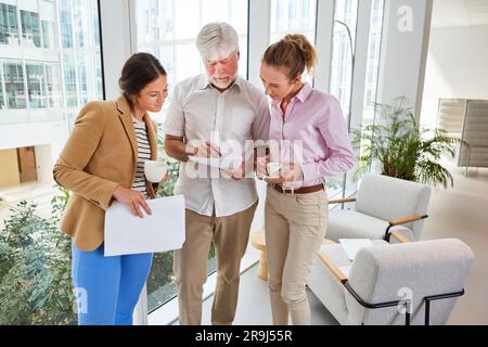 Senior businessman discussing over documents with female colleagues Stock Photo
