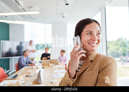 Happy female professional talking on smart phone at workplace Stock Photo