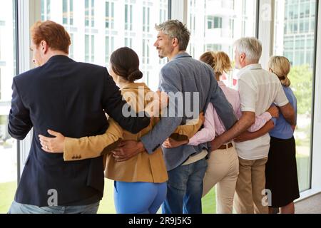 Rear view of business professionals standing with arms around Stock Photo