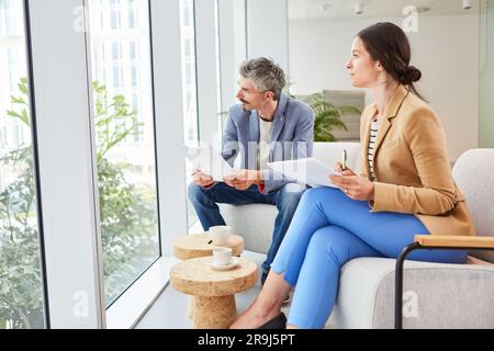 Thoughtful female and male colleagues sitting together with documents Stock Photo