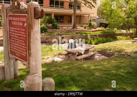 An older man and woman sit at picnic table in grassy area by the Santa Fe River near a historical marker dedicated to Mother Magdalen and the Sister. Stock Photo