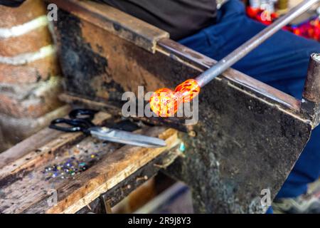 Old craftsman with scissors cutting and blowing the glass in fusing ...