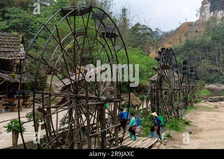 Cat Cat Village, Sapa, Vietnam-April 2023; Water wheels for power generation and made of bamboo and vines lined up in the village with some locals pas Stock Photo