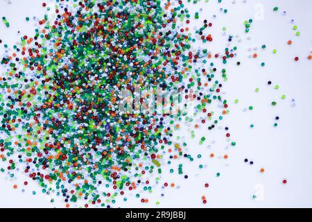 Small multi-colored beads on a white background. Stock Photo