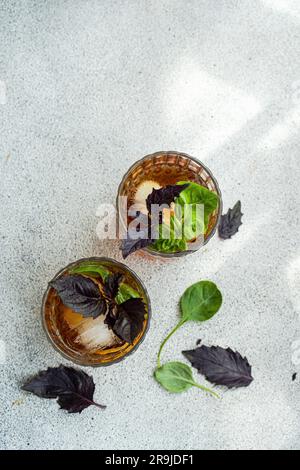 Glass of cocktail with tonic and fresh basil herb leaves Stock Photo