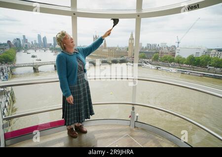 Mrs Doubtfire, played by Gabriel Vick in the musical production in London's West End, gives a pod on the lastminute.com London Eye a clean - reenacting the iconic cleaning scene from the 1993 movie. The comedy musical based on the original film is currently playing at the Shaftesbury Theatre in London. Picture date: Tuesday June 27, 2023. Stock Photo