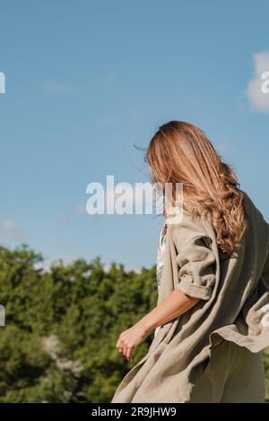 Back view of faceless female in casual outfit picking up wild flowers while resting on green meadow on summer weekend Stock Photo