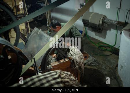 High angle of adult male worker in casual clothes standing near workbench and working in professional workshop Stock Photo