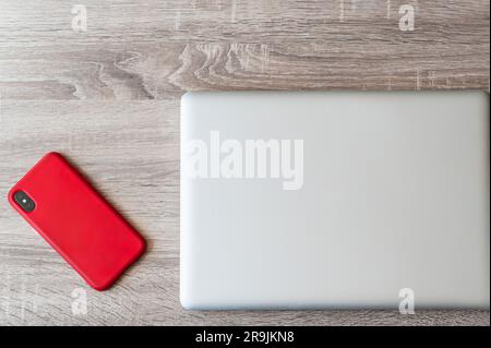 Top view of mobile phone near laptop placed on wooden surface in daylight Stock Photo
