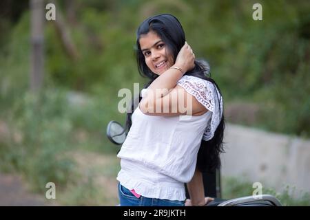 An Indian beautiful young girl with scooter smiling and having fun Stock Photo