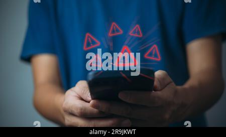 Businessman programmer, developer using smartphone with triangle caution warning sign for notification error and maintenance concept. Stock Photo