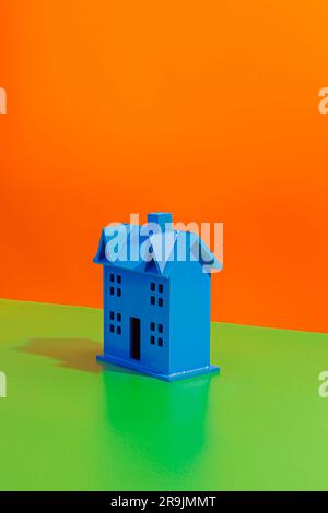 Side view of blue colored miniature of house model placed on bright orange and green background Stock Photo