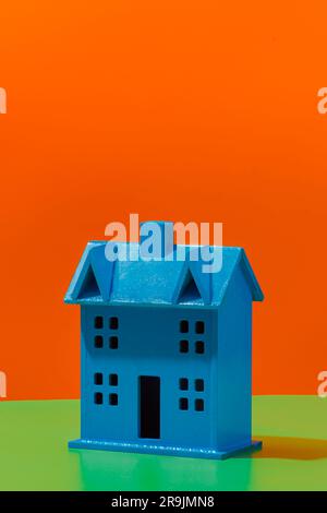 Front view of blue colored miniature of house model placed on bright orange and green background Stock Photo