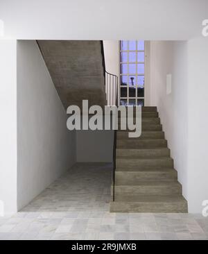 Interior design of spacious hallway with gray walls and marble floor while staircase with railing leading to upstairs near window Stock Photo