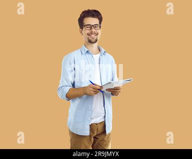 Cheerful man student or young professor standing with notebook and pen Stock Photo
