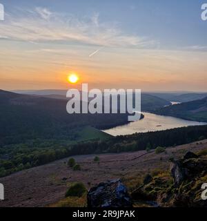 The photo shows a sunset at Bamford Edge in the Peak District. The sky is filled with vibrant shades of orange, pink, and purple, creating a stunning Stock Photo