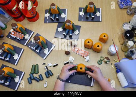 Seiffen, Germany. 27th June, 2023. An employee of Seiffen folk art glues together smoking figures "climate glue". A small man in an orange vest sits on a gray background, the smoke comes out of his ears. In 2021, the people of Seiffen had already put a "Smoking Merkel" on the market and sold quite a few thousand of them. Since last year, you can also buy the top politicians of the federal government of the traffic light as smoking figures with them. Credit: Jan Woitas/dpa/17�Թ����� Live News Stock Photo
