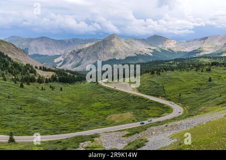 Cottonwood Pass - A Summer day panorama of a mountain road winding in a green valley at east of  the summit of Cottonwood Pass. Crested Butte, CO, USA. Stock Photo