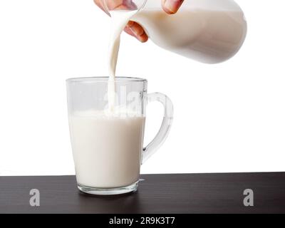 Milk is poured from a bottle into a glass. Milk on a light background. Stock Photo