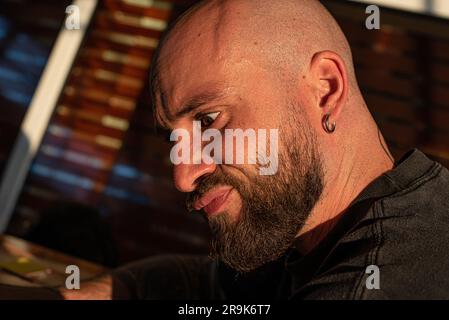 close-up of a man with a shaved head and a black beard with a crazy expression. Stock Photo