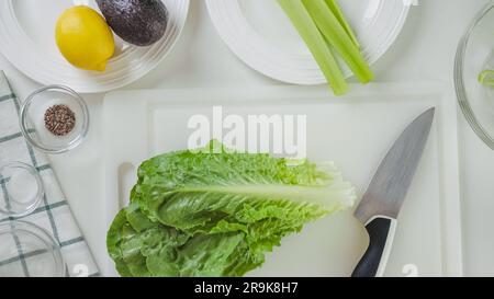 Fresh green Romain lettuce on cutting board. Celery lettuce salad recipe, ingredients close-up on white background, flat lay Stock Photo