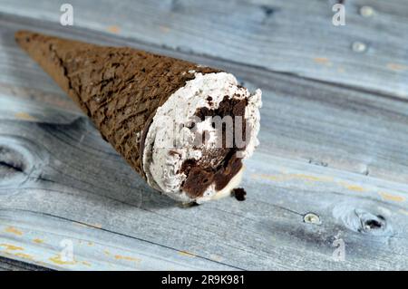 Ice cream of cocoa chocolate and vanilla cone with topping of chocolate chips cookies pieces in crispy wafer cones, melting cold ice cream twirl with Stock Photo