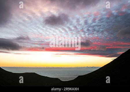 Scenic clouds in the sky at dawn over silhouettes of cliffs surrounding Gjogv, Eysturoy Island, Faroe Islands Stock Photo