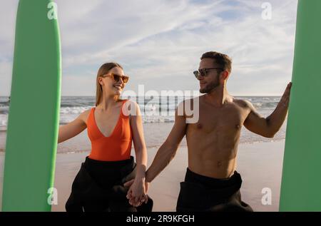 Portrait Of Beautiful Young Surfers Couple With Surfboards Posing On The Beach Stock Photo