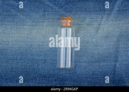 small glass test tube with cork cap on an isolated jeans Stock Photo