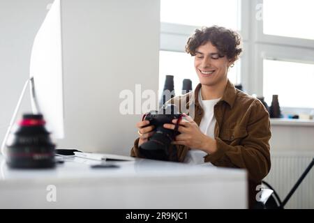 Modern arts and creative career concept. Happy smiling photographer man holding camera using computer Stock Photo