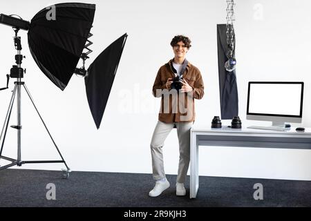 Happy european male photographer with dslr camera posing in his own modern photostudio, looking at camera and smiling Stock Photo