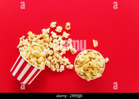 Striped round box with popcorn on a bright red background. Top view, copy space for text Stock Photo