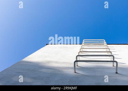 Abstract architecture background, white wall with metal stairs under blue sky, fire escape way Stock Photo