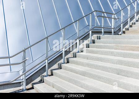 Abstract modern architecture background with a stairway going up near shiny gray metal roof Stock Photo