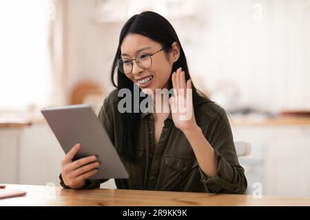 Cheerful young chinese woman using digital tablet at kitchen Stock Photo
