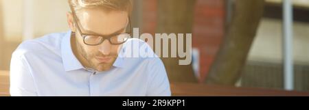 Business message. Focused businessman using smartphone and drinking coffee while sitting on the bench outdoors Stock Photo
