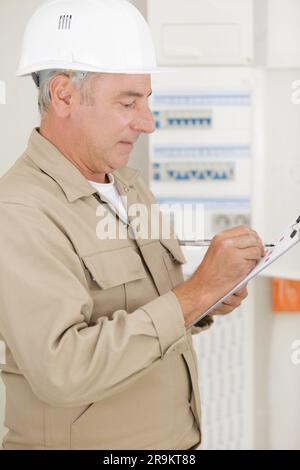 senior tradesman writing on clipboard Stock Photo