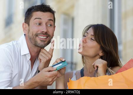 boyfriend asking for a kiss in exchange for credit card Stock Photo