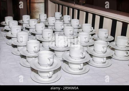 bar at an outdoor ceremony. Lots of cups and saucers on the table. pyramid of cups and saucers for the holiday. Tea cups catering and serving at a ban Stock Photo