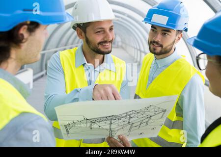 engineer looking over building plans with construction workers Stock Photo