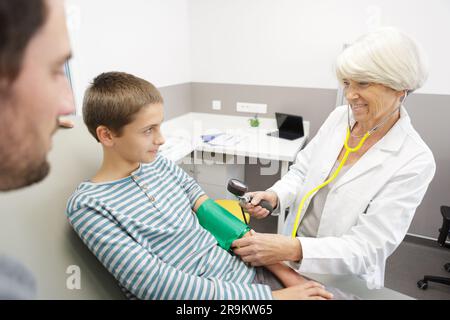 mature female doctor takes a childs blood pressure Stock Photo