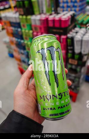 Hand holding a can of monster energy drink in the grocery store Stock Photo
