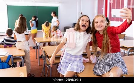 Happy schoolgirls taking selfie with phone at recess between lessons Stock Photo