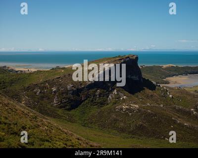 Green grass covered mountain hill near blue ocean, coastal nature landscape at Cape Farewell, Tasman South Island New Zealand Stock Photo