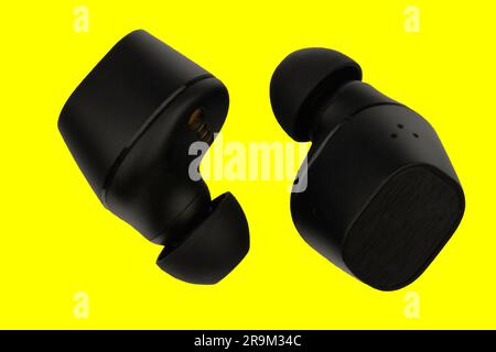 Wireless stereo earbuds. Black wireless earphones. Earbuds or headphones isolated on yellow background with clipping path. Macro horizontal image. Ext Stock Photo